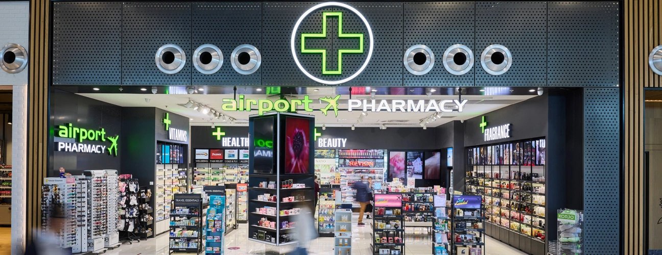 Airport Pharmacy storefront with illuminated green pharmacy cross